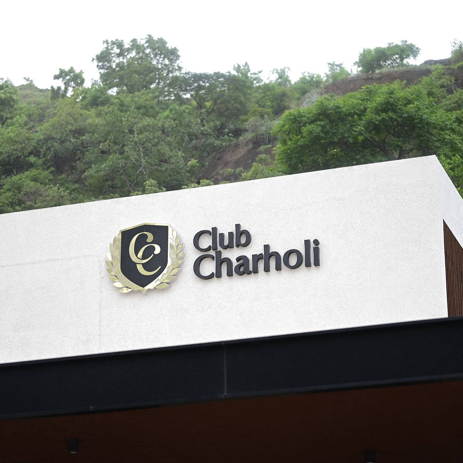 a close up image of the club charholi, pune logo ona white walled building